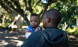 A father holds his son, on a street near his office at the Department of Health in central Cape Town, South Africa. He participated in a UNICEF-supported program that promotes men’s involvement as equitable caregivers.