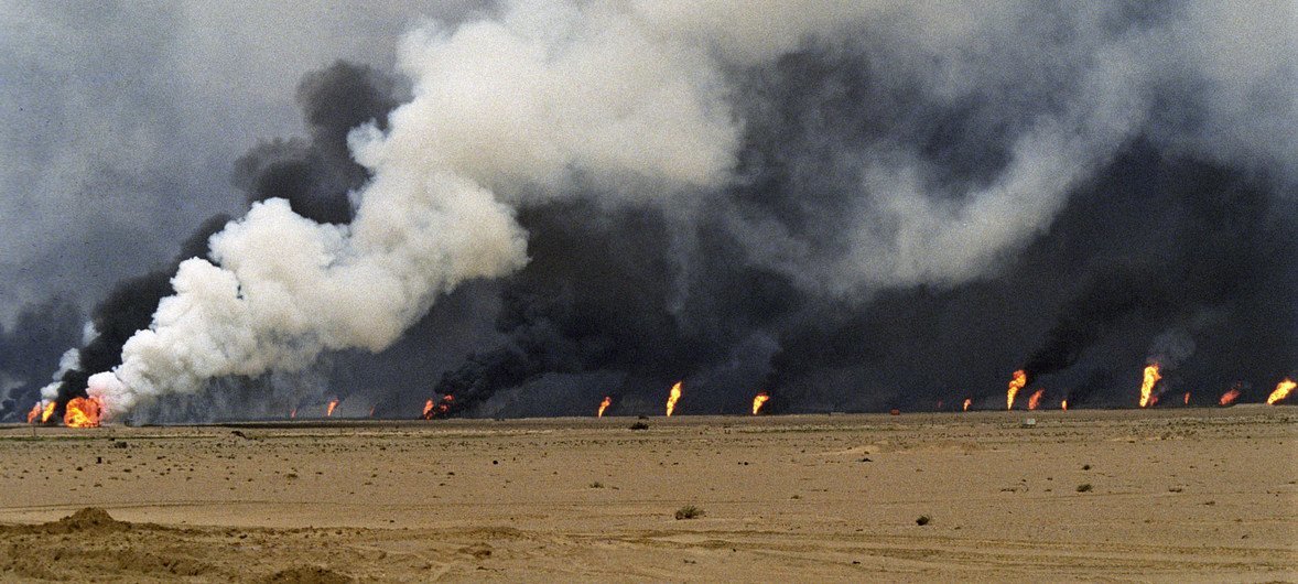 The burning of an oil well by the Iraqi forces in the fields of Al-Muqwa.  In the foreground is a lake of oil due to uncovered oil wells.  30 March 1991.