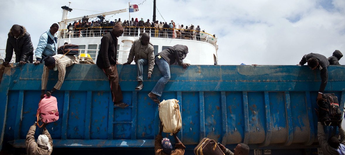 लीबिया के बेनगाज़ी बंदरगाह पर अंतरराष्ट्रीय प्रवासी संगठन के एक जहाज़ से सामान उतारते हुए अन्य देशों के नागरिक. (2011)