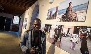 المصور اللاجئ محمد كيتا، 25 عاما، من ساحل العاج - مع صوره الفوتغرافية خلال مهرجان بينالي فينيسيا الفني. 
