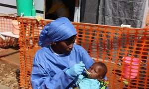 Mhudumu wa afya anayehusika na kuhudumia wagonjwa wa Ebola akiwa amevalia mavazi sahihi ya kujikinga huku akimlisha mtoto kwenye kituo cha tiba dhidi ya Ebola huko Kivu Kaskazini nchini DRC. ( 30 januari 2019)