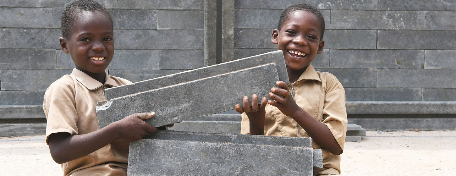 Niños felices porque su nueva aula de clase está siendo construida con ladrillos de plástico en Côte d'Ivoire.