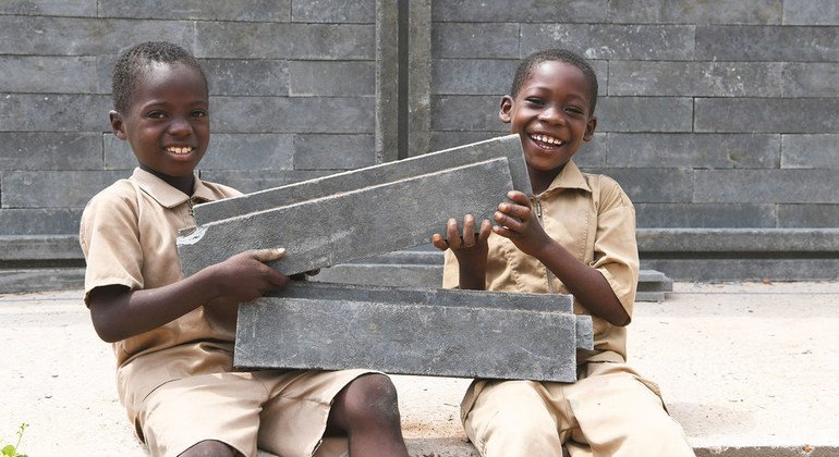 Niños felices porque su nueva aula de clase está siendo construida con ladrillos de plástico en Côte d'Ivoire.